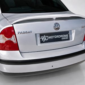 Rear view of a silver Volkswagen Passat, showing taillights, badges (PASSAT, 2.0T) and a dark Motordrome Design plate on the trunk team area