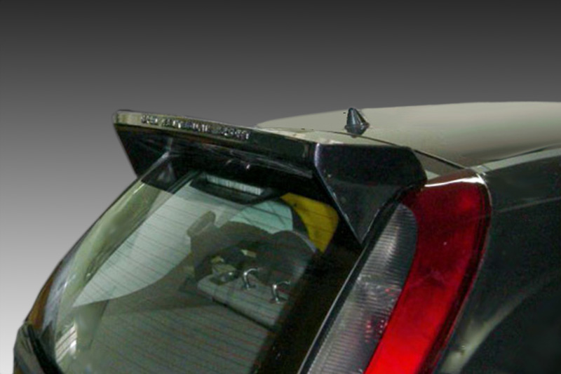 A-249_1jpg - OPSHOLDERS Back of a dark hatchback car showing a small lip spoiler above the rear window, with the red tail light to the right.
