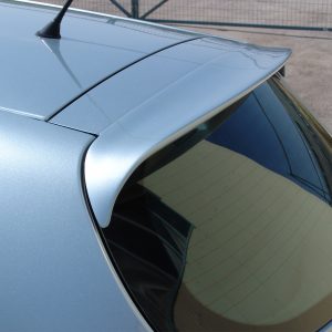 Blue car rear hatch with a small spoiler mounted at the edge of the window. The rear window shows defroster lines and a wiper is visible on the side.