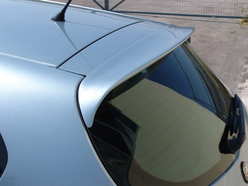 Blue car rear hatch with a small spoiler mounted at the edge of the window. The rear window shows defroster lines and a wiper is visible on the side.