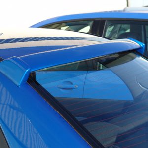 Close-up of a blue car's rear area with a roof spoiler and tinted rear window; another blue car is visible in the background.