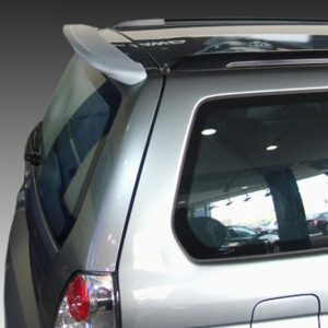 Rear quarter view of a silver SUV with a spoiler, showing the back window and tail light area in a showroom setting.
