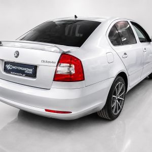 White Skoda Octavia seen from the rear in a studio, with a dark rear window and red taillights.