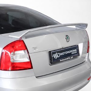 Rear view of a silver sedan showing trunk spoiler, taillight, and a dealership plate reading 'Motorodome Design'