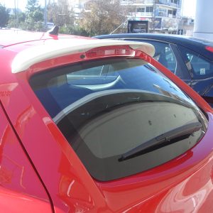 Red hatchback with a white rear spoiler parked next to a dark blue car in a sunny parking lot.