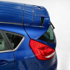 Blue hatchback rear with integrated roof spoiler and red taillight highlight the design detail.
