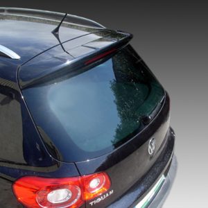 Rear three-quarter view of a dark blue Volkswagen Tiguan SUV with roof rails and red tail lights.