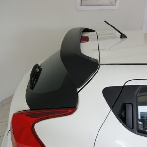 SONY DSC - OPSHOLDERS Rear view of a white SUV showing a black rooftop spoiler, antenna, and red taillights in a showroom setting.
