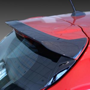 Close-up of a red car's rear spoiler mounted on the trunk, with a curved windshield in the foreground.
