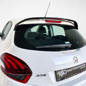 Rear view of a white Peugeot 208 hatchback with red taillights and a rear spoiler in a studio setting