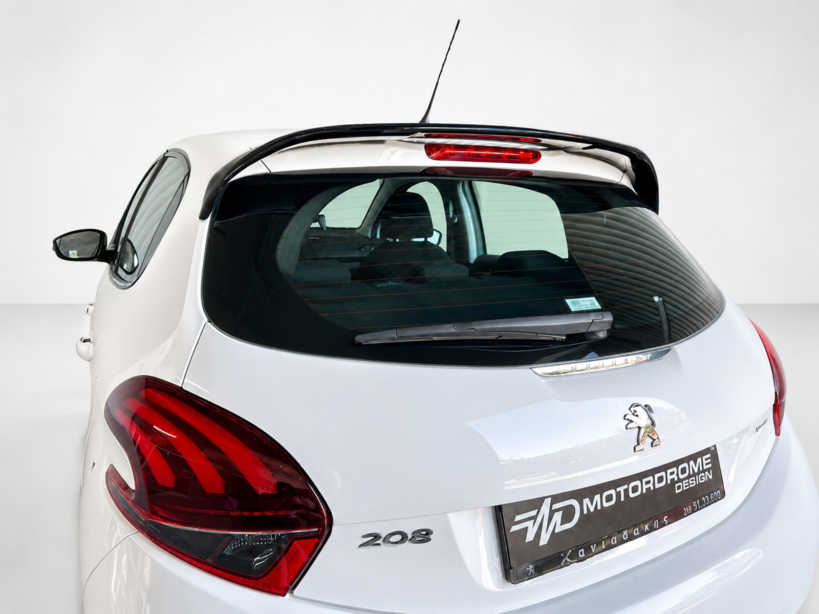 A-397_1jpg - OPSHOLDERS Rear view of a white Peugeot 208 hatchback with red taillights and a rear spoiler in a studio setting