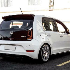Rear three-quarter view of a white Volkswagen hatchback with dark rear window, lowered suspension, and large silver multi-spoke wheels in a parking lot