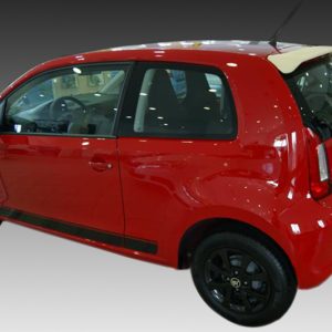Red compact hatchback car photographed from the side and rear, featuring black wheels and a small rear spoiler