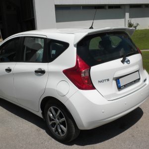 White Nissan Note hatchback parked in a sunny parking lot, rear three-quarter view with taillights visible