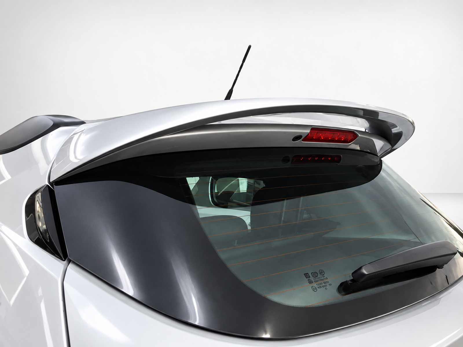 A-409_1jpg - OPSHOLDERS Rear view of a silver hatchback showing a raised spoiler, rear windshield with defroster lines, and the rear wiper at the bottom edge of the window