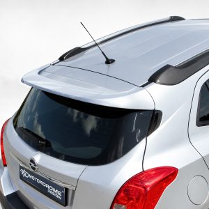 A-409_2jpg - OPSHOLDERS Rear view of a silver SUV featuring a roof spoiler, antenna, and prominent red taillights.