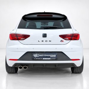 Rear view of a white SEAT Leon FR hatchback in a studio setting, showing taillights and dual exhausts intact at the left. Review: no people visible.