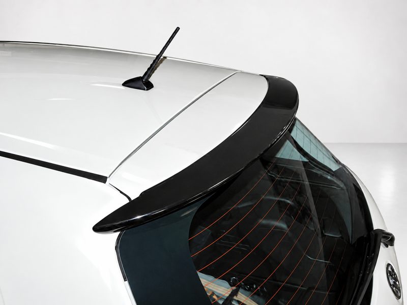 Close-up of the rear of a white hatchback, showing the roof antenna and curved rear window with defroster lines.