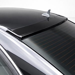 Close-up of a dark car roof with a silver shark-fin antenna and a rear window featuring orange defroster lines.