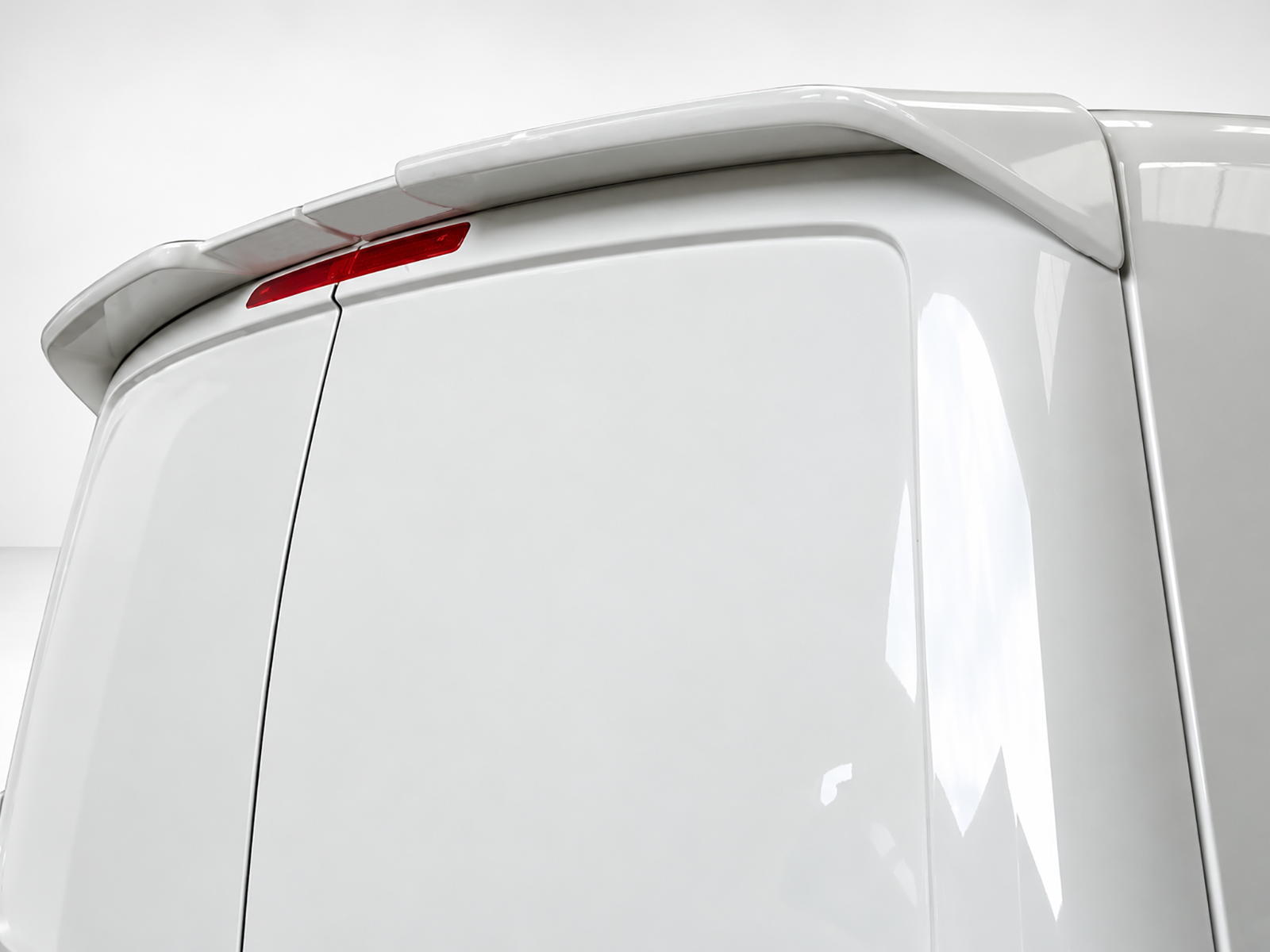 A-418_2jpg - OPSHOLDERS White van rear corner with roof spoiler and red rear brake light, close-up view.