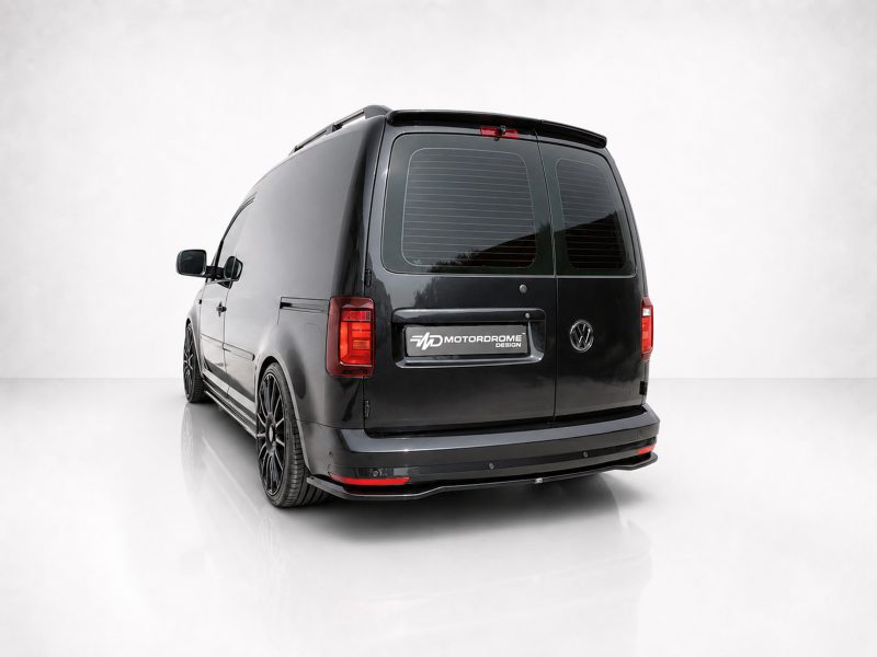 Rear three-quarter view of a black customized Volkswagen van with aftermarket wheels and a Motordrome Design badge.