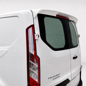 Rear view of a white Ford Transit Custom van, showing the tall vertical taillight and rear window with defroster lines (logo visible).