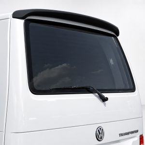 Rear quarter view of a white VW Transporter van, showing the rear window with wiper and a small roof spoiler.