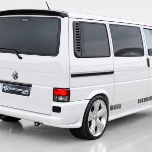 A-421_2jpg - OPSHOLDERS White VW minivan shown from rear and side, featuring large chrome aftermarket wheels and gray decal accents along the lower body plate reading Motordrome Design