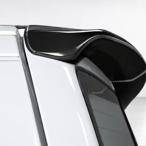 Close-up of a glossy black rear spoiler mounted on a white car, seen from the side.
