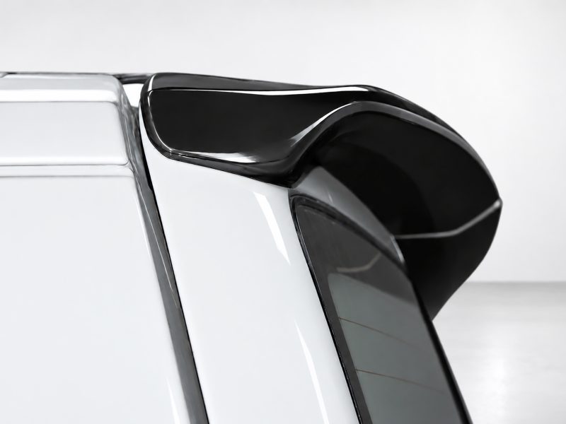 Close-up of a glossy black rear spoiler mounted on a white car, seen from the side.