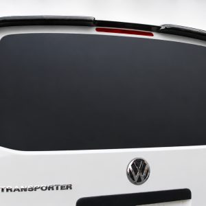 A-423_2jpg - OPSHOLDERS Rear view of a white Volkswagen Transporter van with a large dark rear window and VW badge visible on the tailgate, slight spoiler across the top edge.