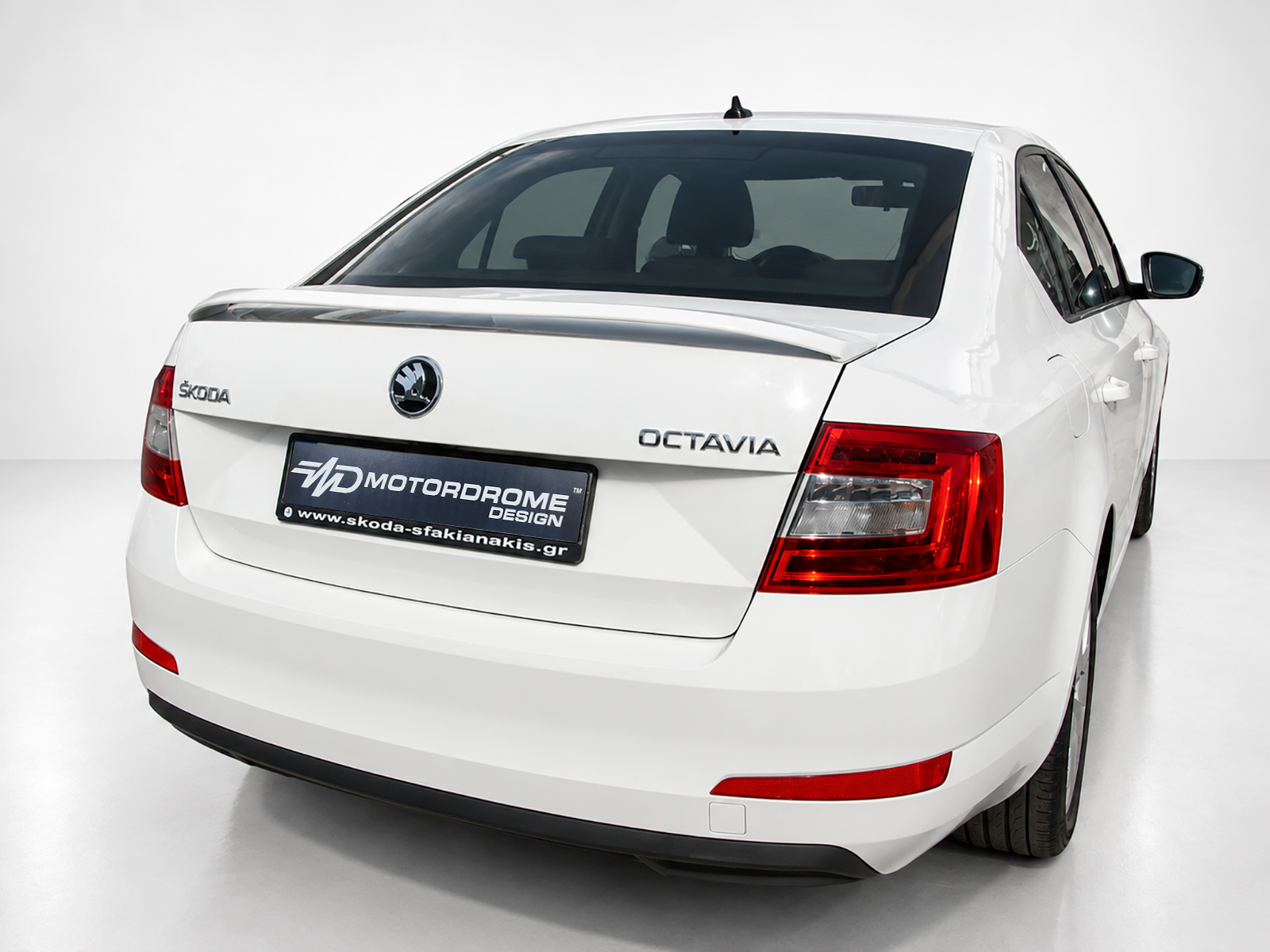 A-429_1jpg - OPSHOLDERS White Skoda Octavia rear view in a studio, showing logo, model badge, and a black plate with Motordrome Design text in the center