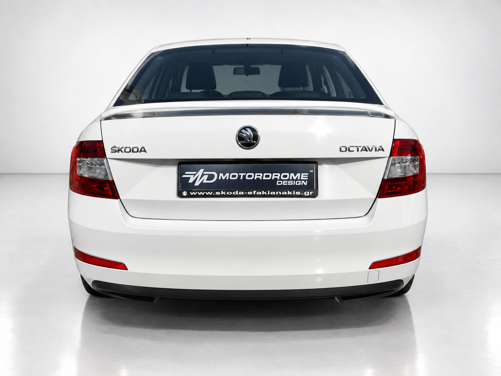 A-429_2jpg - OPSHOLDERS Rear view of a white Skoda Octavia with taillights, logo, and a Motordrome Design dealership plate in the center
