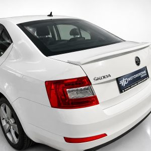 A-429_3jpg - OPSHOLDERS Rear three-quarter view of a white Škoda sedan, showing the trunk spoiler, taillights, and emblem.