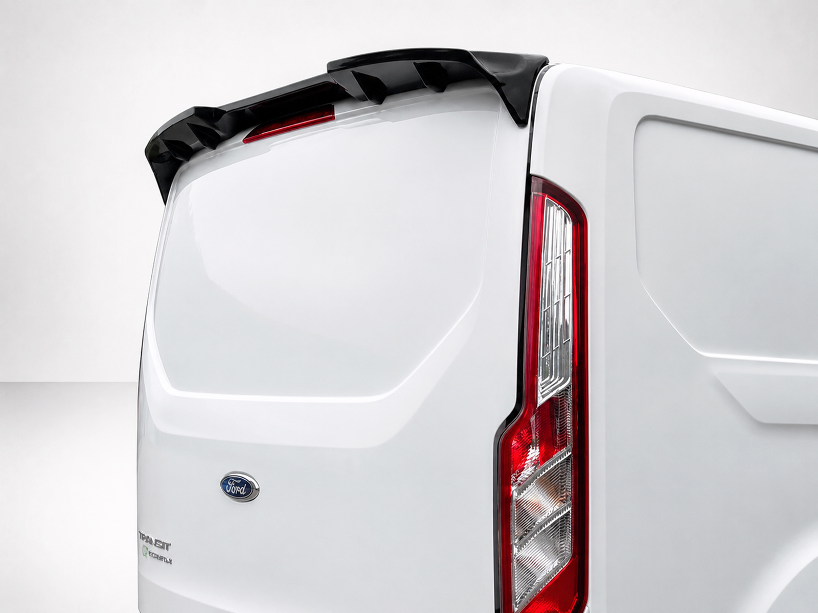 A-434_1jpg - OPSHOLDERS Rear view of a white Ford Transit cargo van showing the tail light and rear door, with a black roof spoiler visible at top edge.