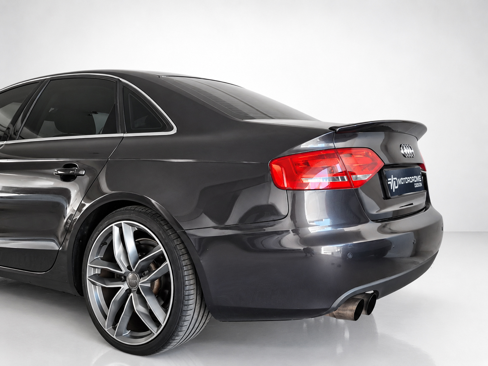 A-443_1jpg - OPSHOLDERS Rear three-quarter view of a dark gray Audi sedan with large alloy wheels in a studio setting.