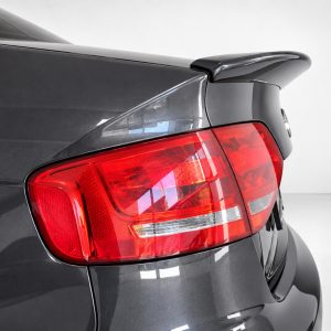 A-443_3jpg - OPSHOLDERS Rear end of a dark gray car showing the red tail light and rear spoiler in a studio setting