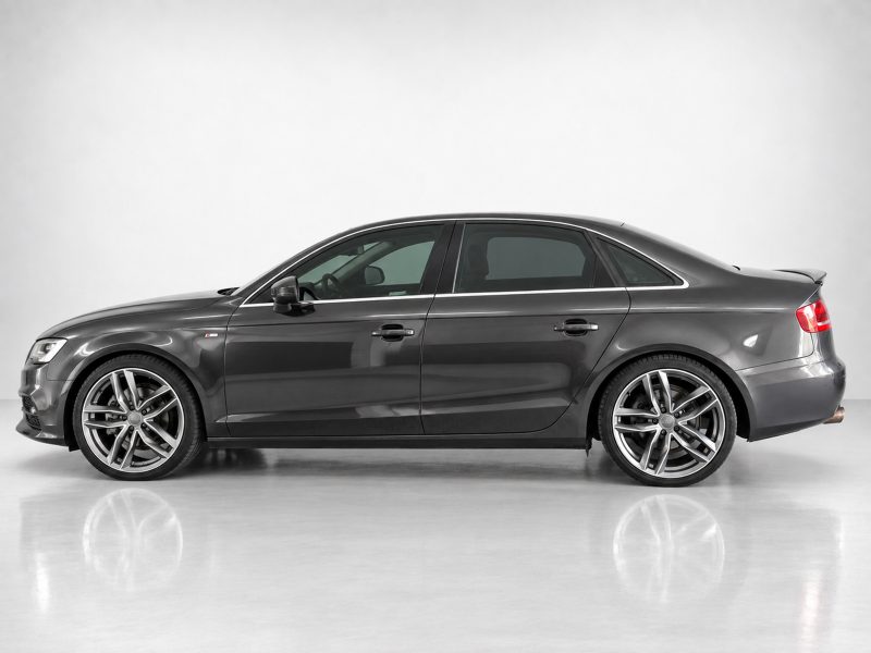 A-443_4jpg - OPSHOLDERS Side profile of a dark gray four-door sedan with large alloy wheels on a reflective studio surface, showing chrome trim.