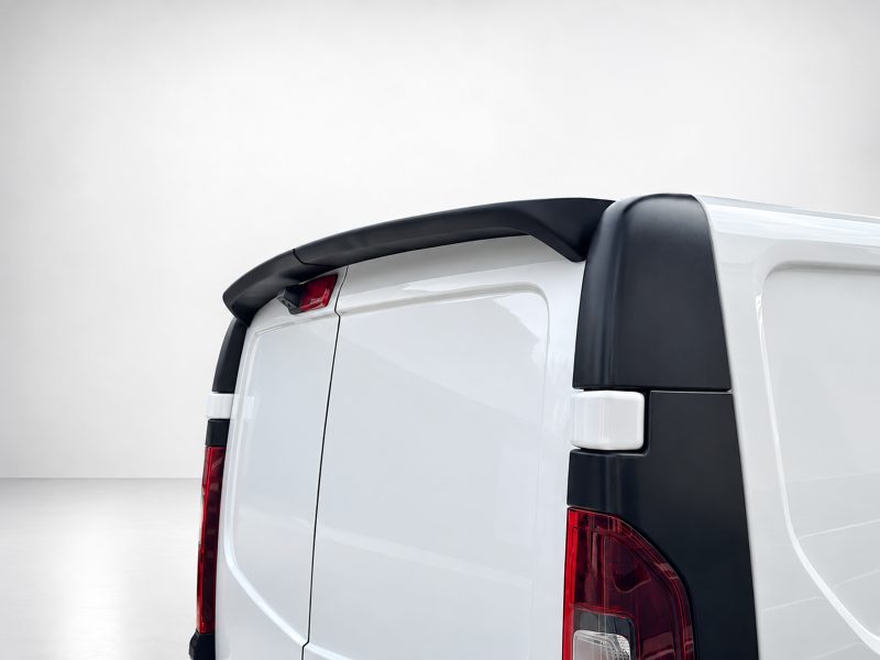 Rear quarter view of a white van with a black roof spoiler and red taillights visible.|