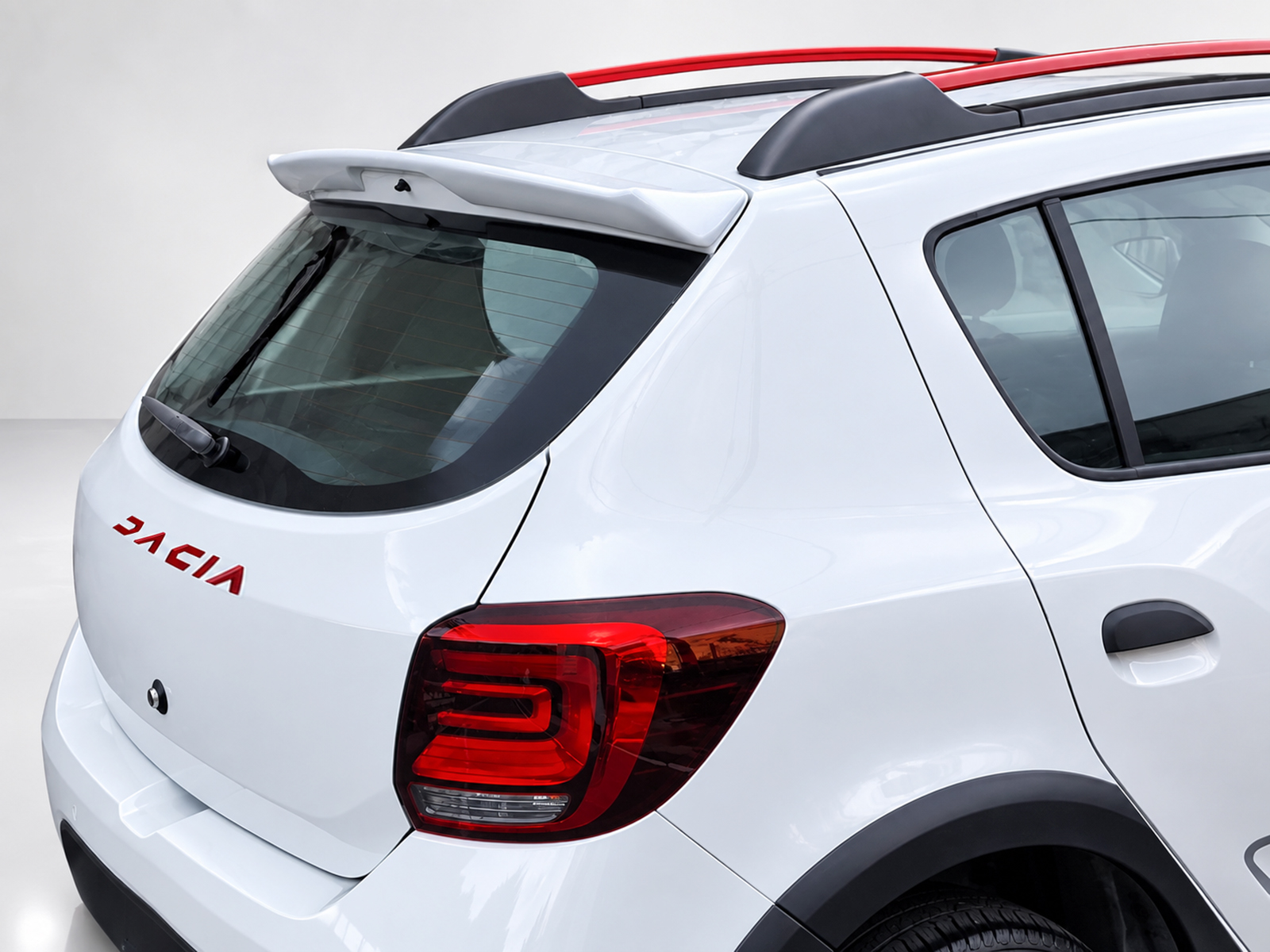 A-445_1jpg - OPSHOLDERS Rear view of a white Dacia SUV with a spoiler, roof rails, and red taillights.