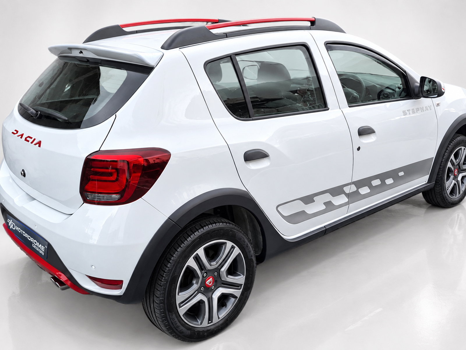A-445_2jpg - OPSHOLDERS White Dacia compact SUV photographed from rear-left side, showing badge, taillight, roof rails, and rear wheel arch