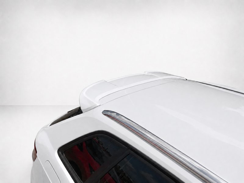 White car roof with spoiler seen from above, showing sleek lines and chrome trim against a pale background.