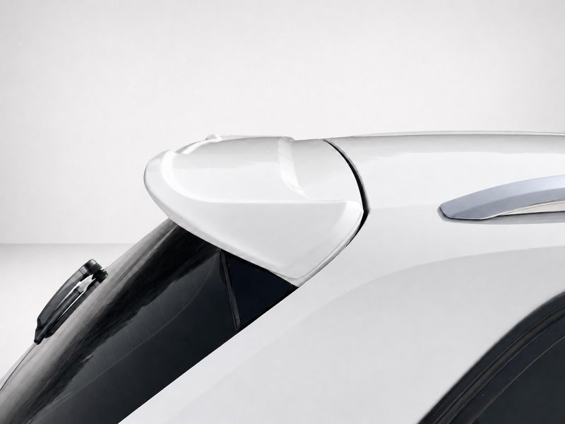 Close-up of a white car's rear spoiler mounted above the rear window, showing aerodynamic curves and glossy finish.