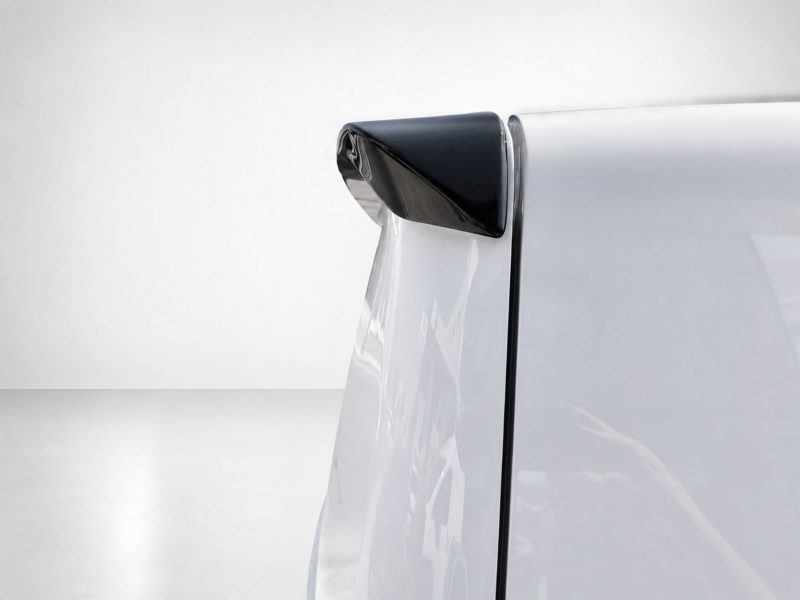 Close-up of a silver car door with a small black curved spoiler at the window edge.