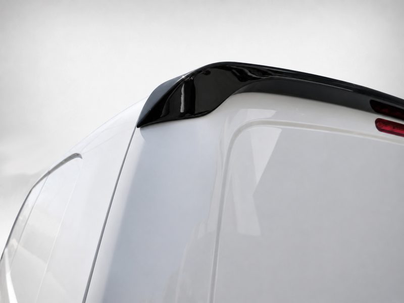 Close-up of a white car's rear end with a glossy black spoiler and red taillight detail on the right.