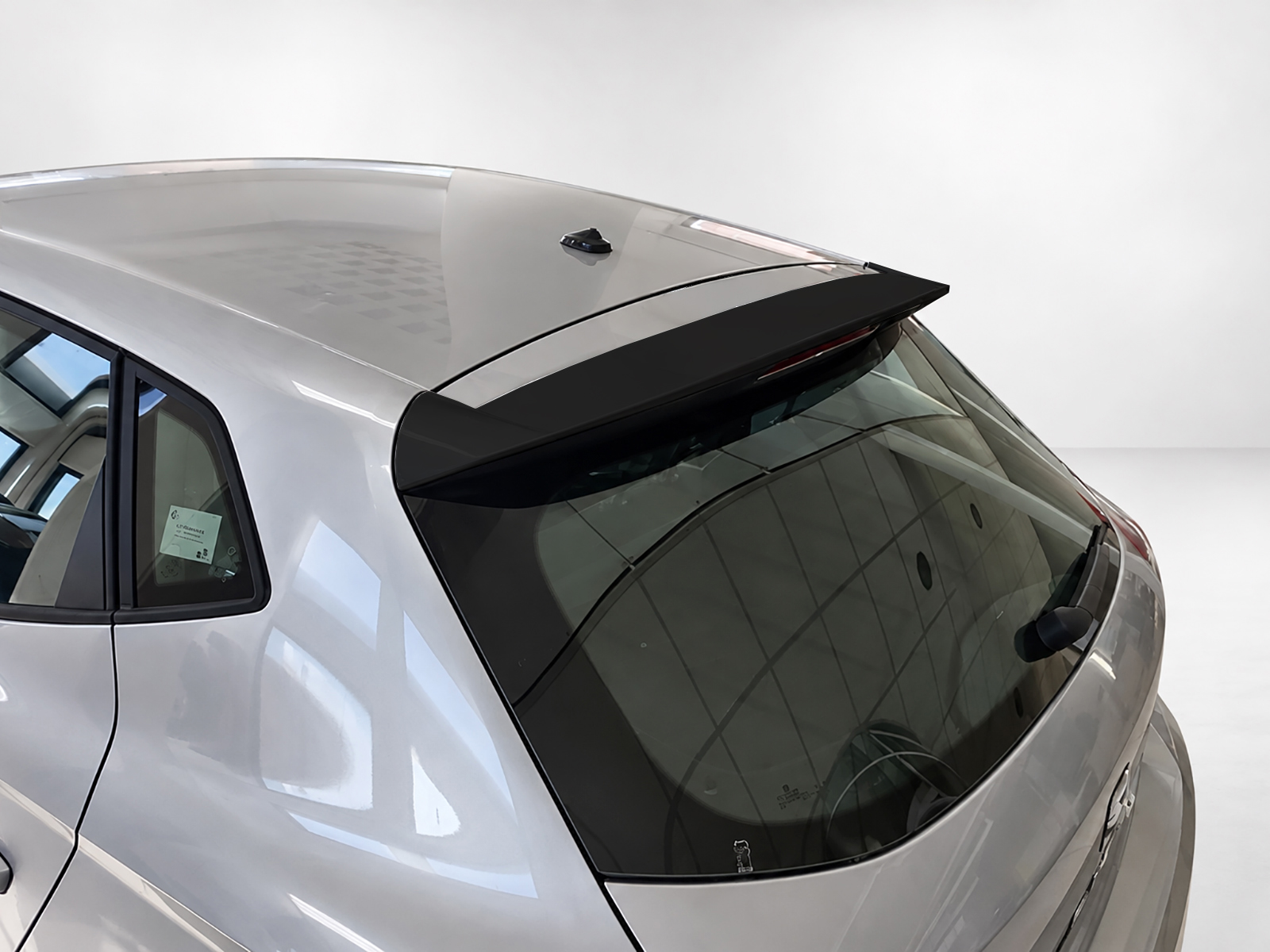 A-451_1jpg - OPSHOLDERS Rear view of a silver hatchback with a black roof spoiler and shark-fin antenna, seen from above.