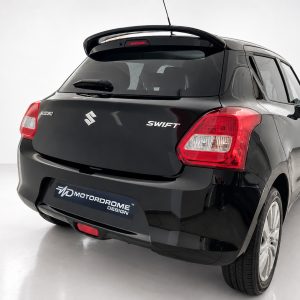 Rear view of a black Suzuki Swift in a studio, showing tail lights and MD MotorDrome Design plate on the bumper.