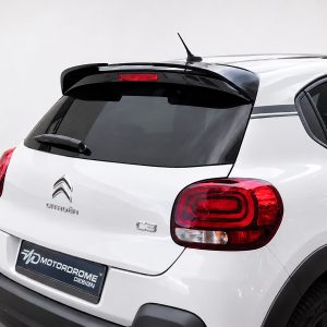 Rear view of a white Citroën C3 with a black rear spoiler, dark hatch window, and red taillights. Antenna on the roof and a dealership plate below.