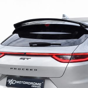 Rear view of a silver hatchback with a black roof spoiler, red taillights, and 'PROCEED' lettering on the trunk.