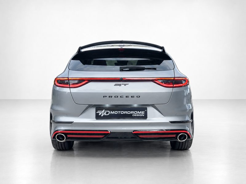 Rear view of a silver SUV hatchback with full-width taillights, 'PROCEED' lettering, and dual exhausts; Motordrome Design plate visible at the bumper edge.